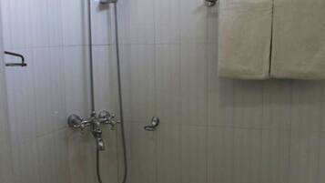 Um banheiro pequeno e revestido com azulejos, com chuveiro, vaso sanitário e banheira.