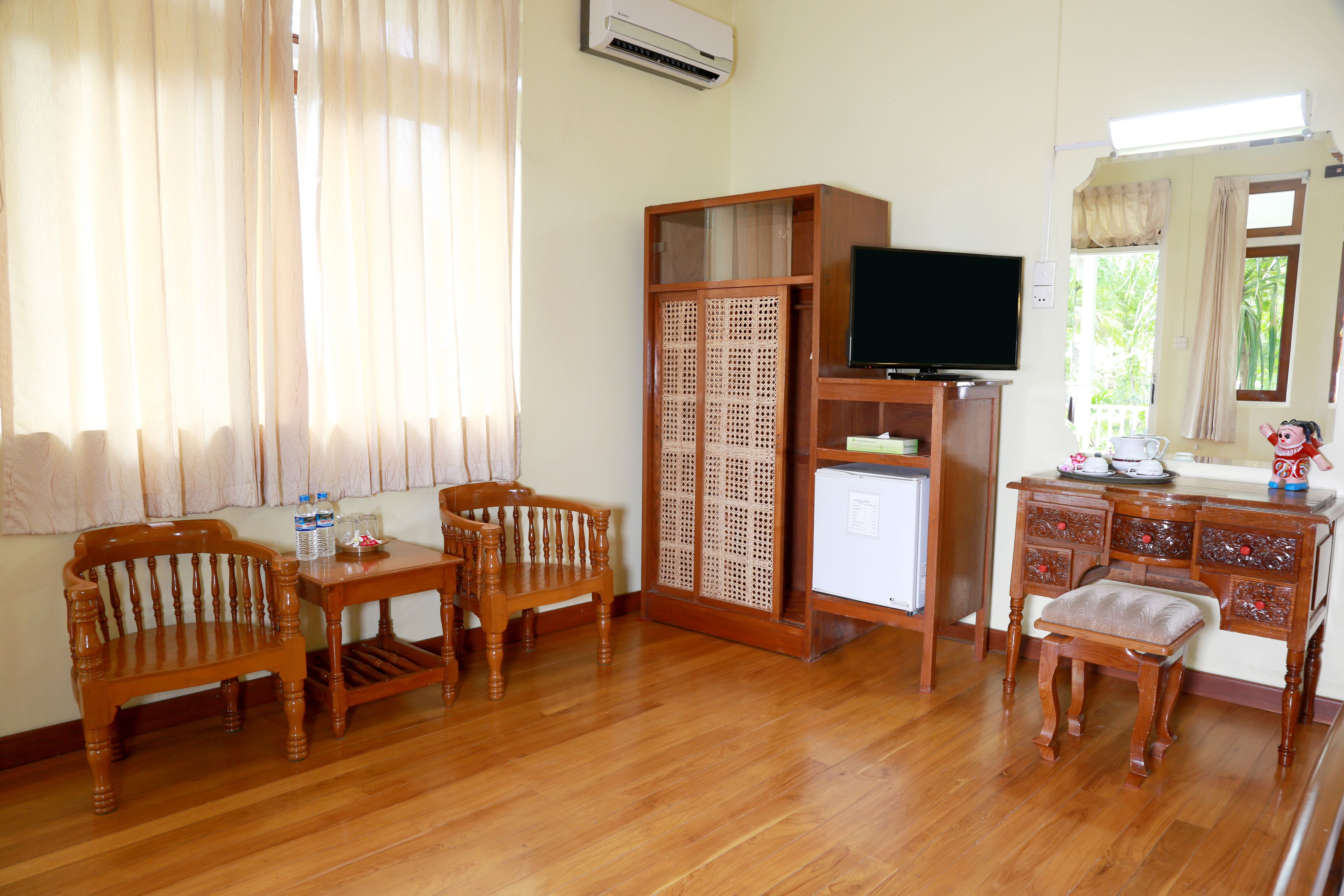 A room with wooden furniture, a television, and a window with curtains.