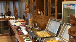 A buffet setup with various food items and a statue.