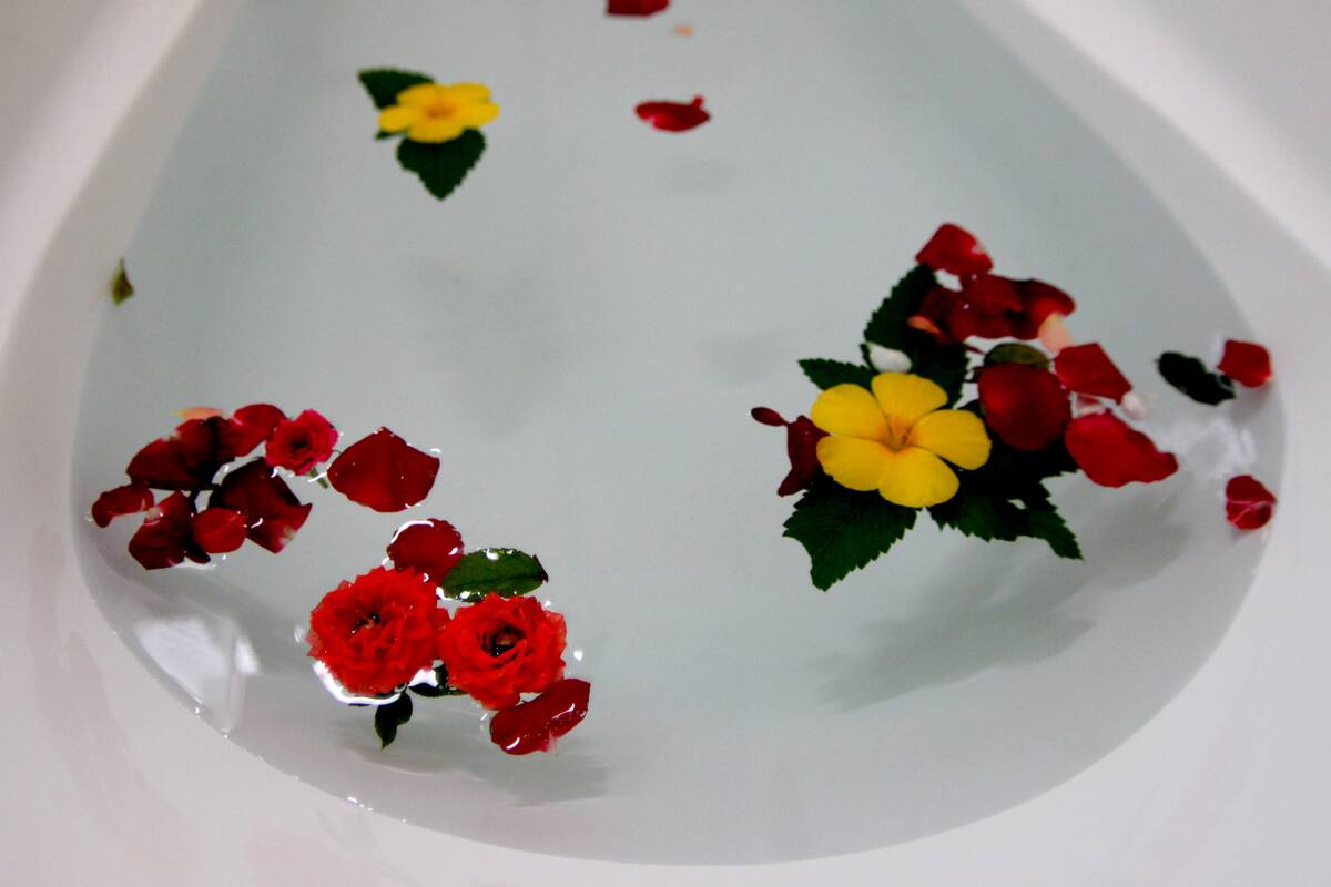 A bathtub filled with water and floating flowers.