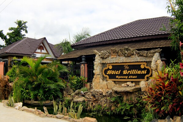 A sign for Hotel Brillant with a tropical garden in front.