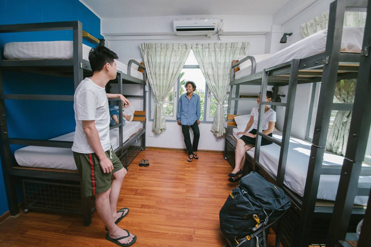 Une chambre de dortoir avec des lits superposés, un plancher en bois et un appareil de climatisation.