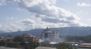A building with a central tower and multiple smaller structures around it, set against a backdrop of mountains and a partly cloudy sky. - Ostello Bello Nyaung Shwe (Nyaungshwe)