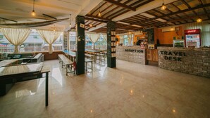 A spacious lobby with a reception desk, a travel desk, and a seating area with tables and chairs. - Ostello Bello Nyaung Shwe (Nyaungshwe)