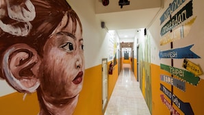 A hallway with a mural of a woman's face and directional signs to various cities. - Ostello Bello Nyaung Shwe (Nyaungshwe)
