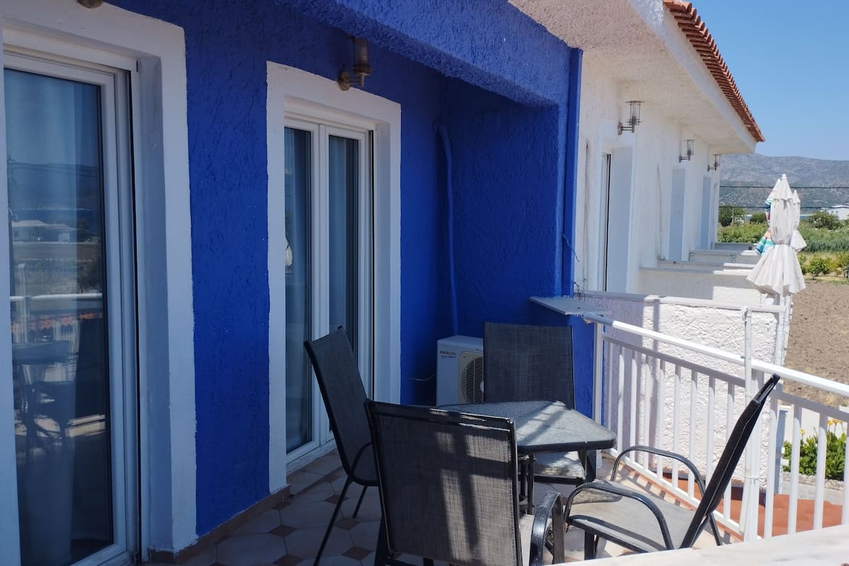 A balcony with a table and chairs, a window, and a view of the landscape.