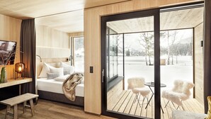 A modern room with a bed, a desk, and a view of a snowy outdoor area. - Alpenhotel Kitzbühel (Kitzbuhel)