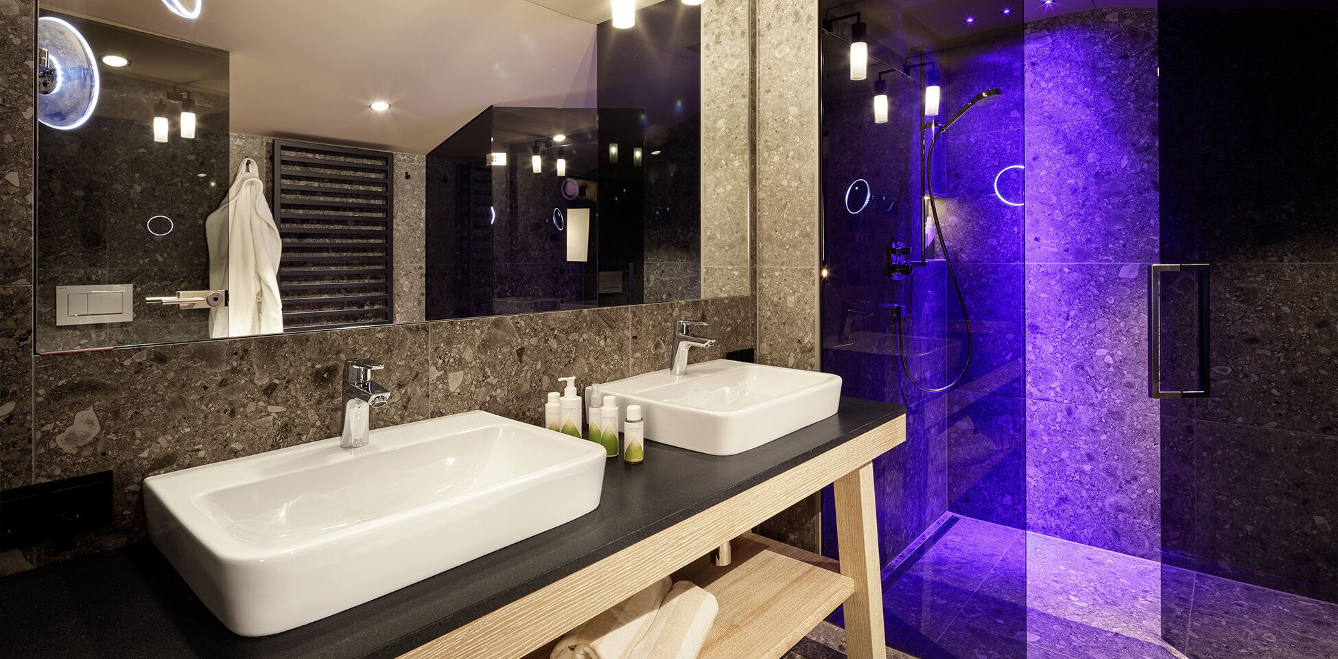 Un baño moderno con dos lavamanos, un espejo grande y una cabina de ducha de vidrio.