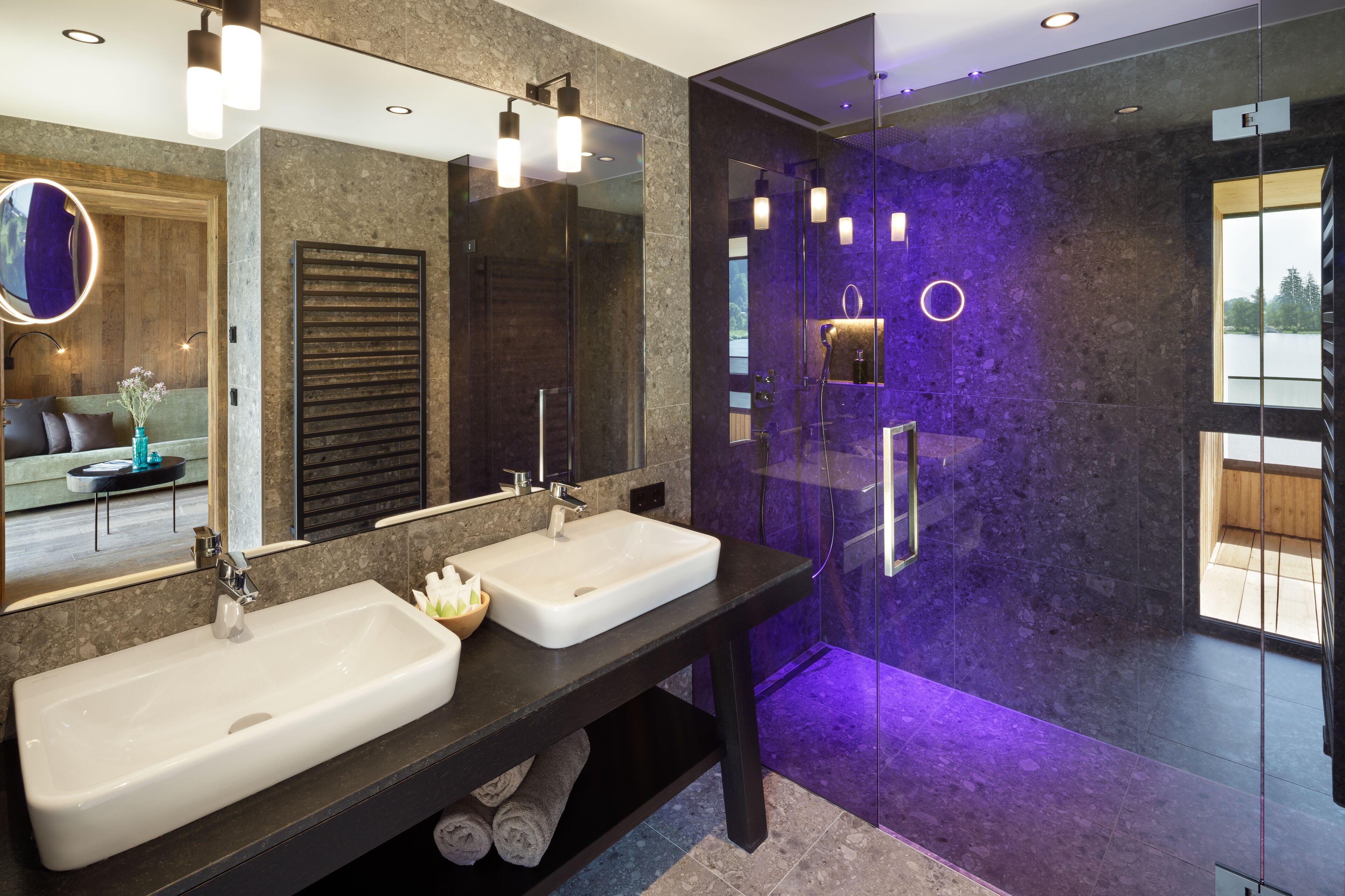 A modern bathroom with two sinks, a large mirror, and a glass-enclosed shower area.
