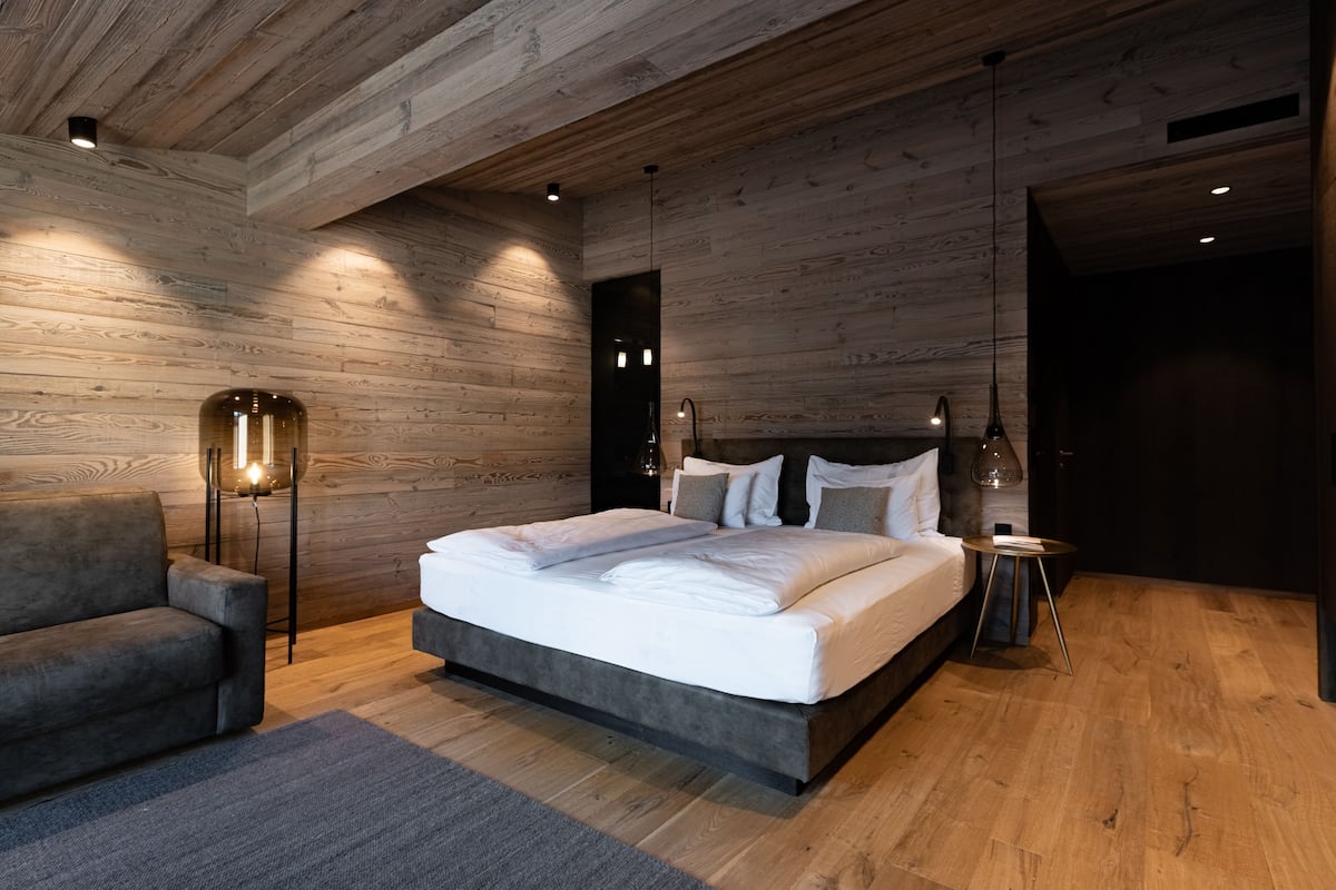 Une chambre moderne avec un grand lit, un canapé et une lampe sur pied.