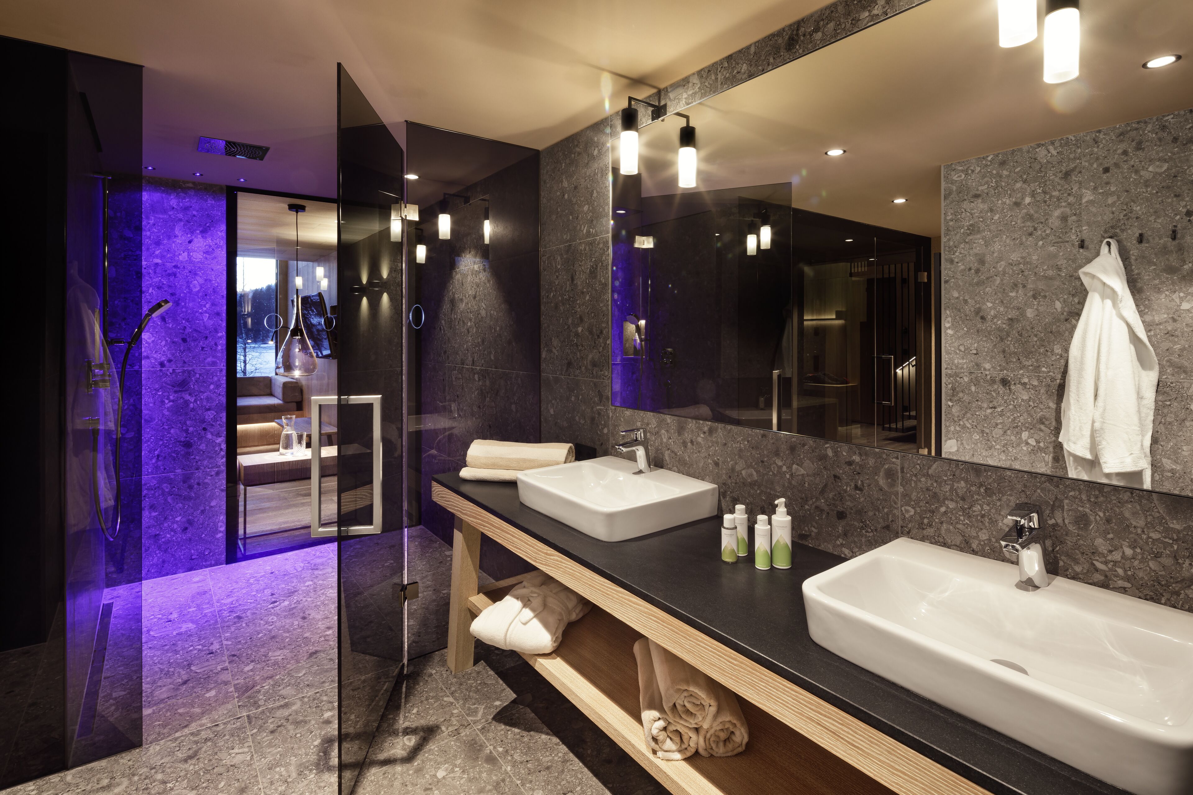 A modern bathroom with two sinks, a large mirror, and a glass shower enclosure.