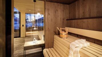 Una sala de sauna con bancos de madera, una mesa con vasos y un cubo de madera.