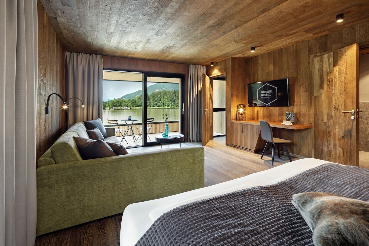 Une chambre d’hôtel moderne avec un grand lit, un canapé vert, un bureau et une télévision.