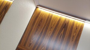 Un coin de pièce avec un mur lambrissé en bois et un mur blanc.