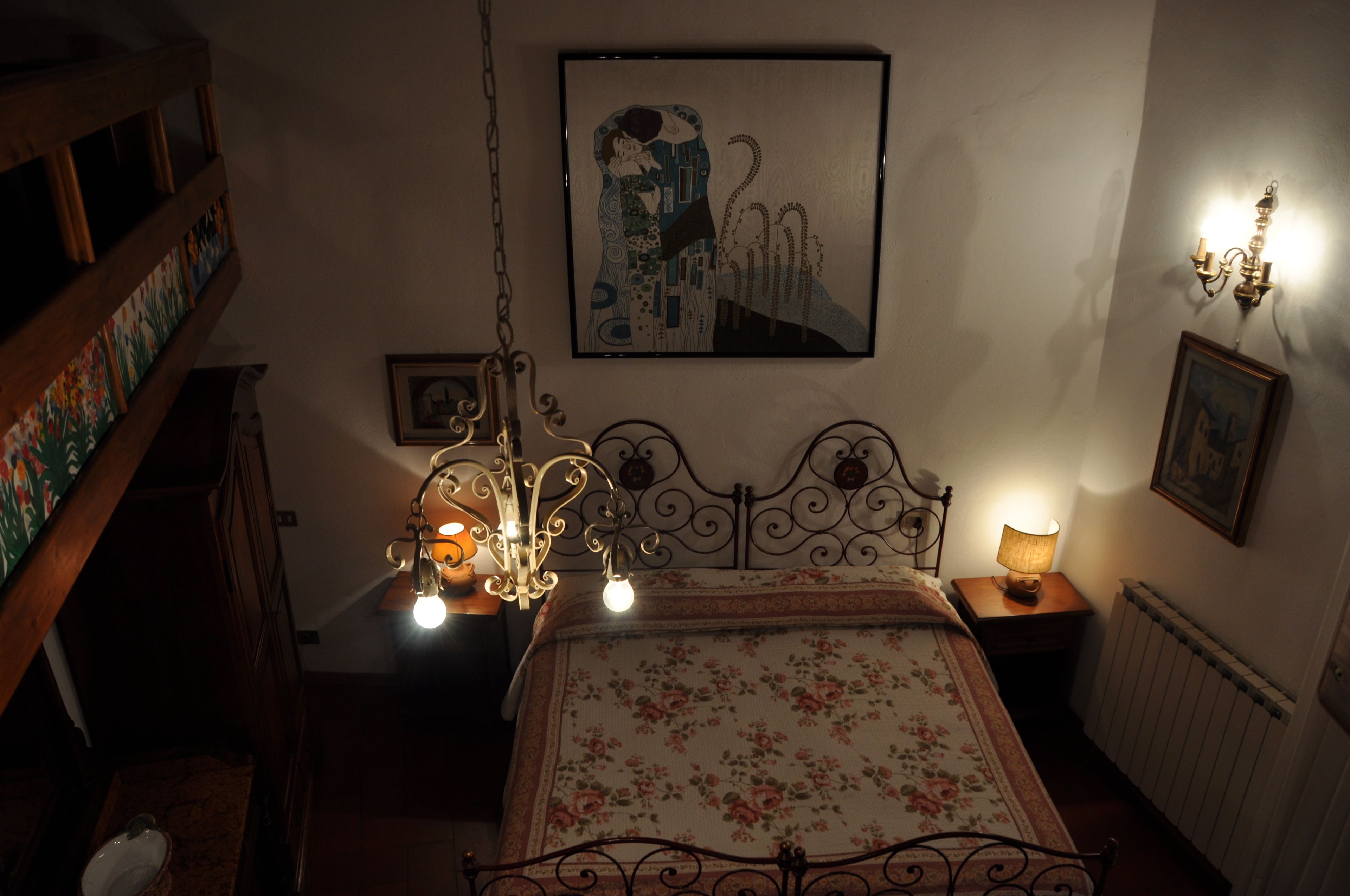 Una camera da letto con un letto, un lampadario, un quadro incorniciato e un termosifone.