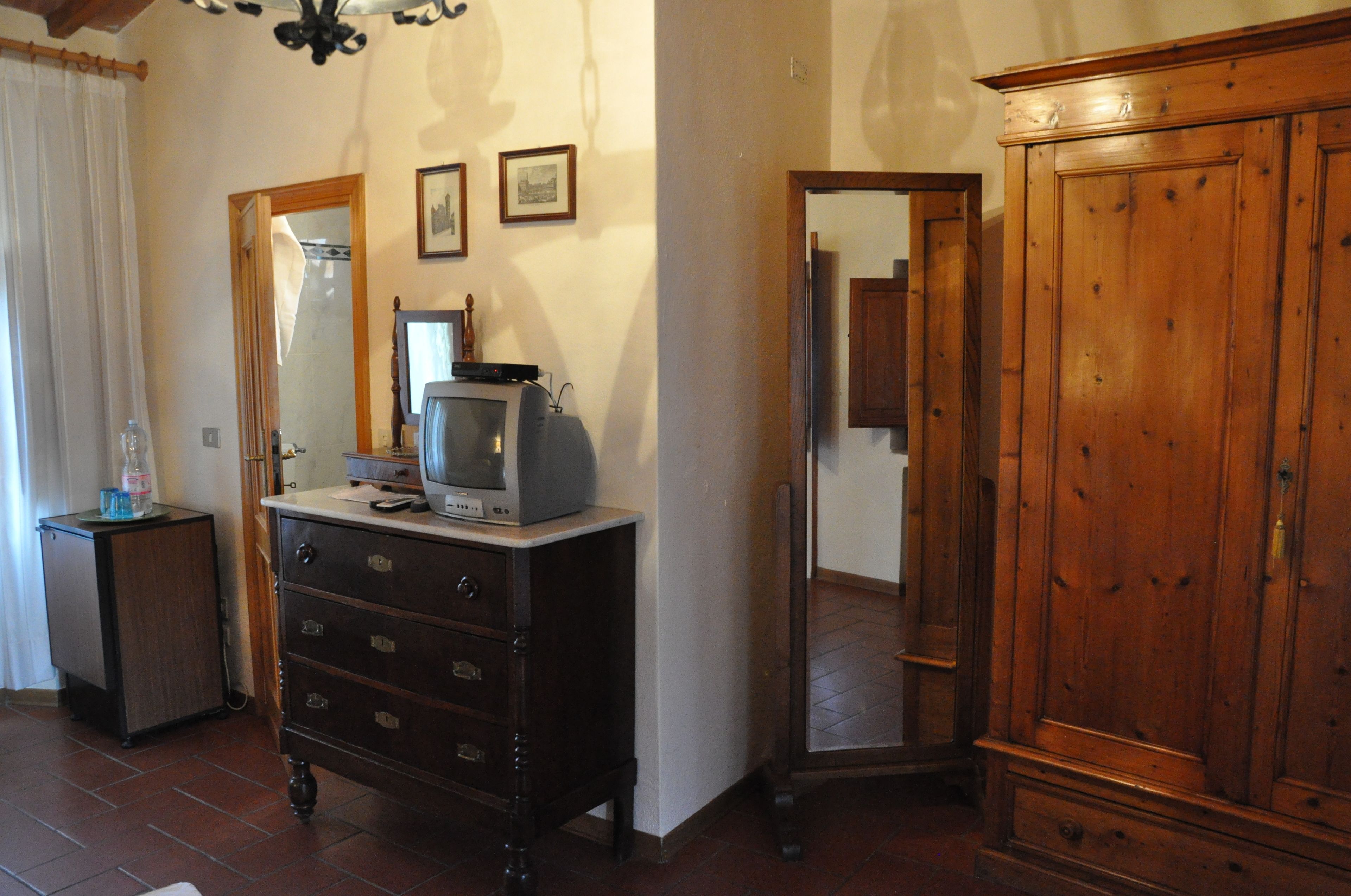 A room with a wooden cabinet, a dresser, and a television on top.