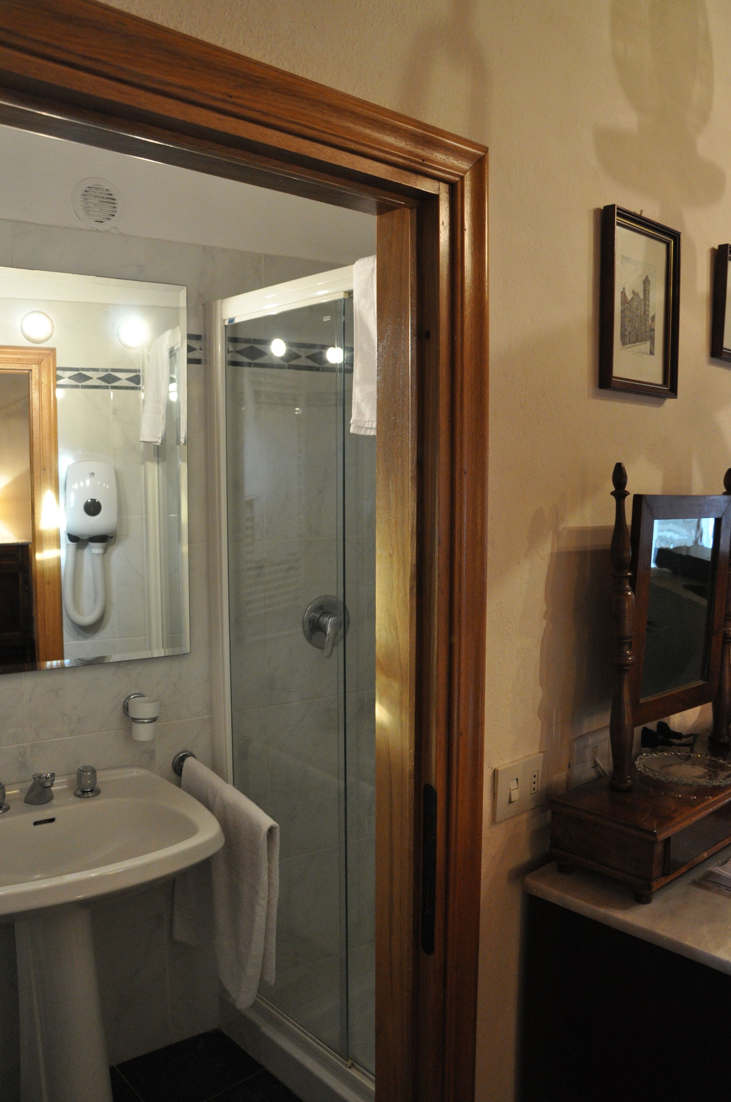 A bathroom with a sink, mirror, and shower.