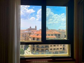 A view through a window with a view of a cityscape, including buildings and a clear sky.