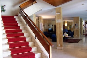 A staircase with red carpet leading to a living area with a TV, sofas, and a coffee table.