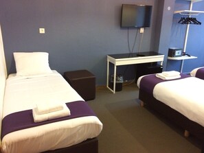 A hotel room with two beds, a desk, a TV, and a wardrobe. - Hotel Bellington (Amsterdam)