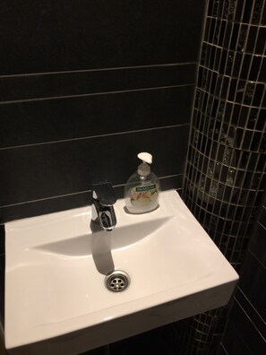 A bathroom sink with a soap dispenser and a faucet. - Hotel Bellington (Amsterdam)