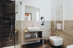 A modern bathroom with a glass-enclosed shower, a white sink, and a bidet.