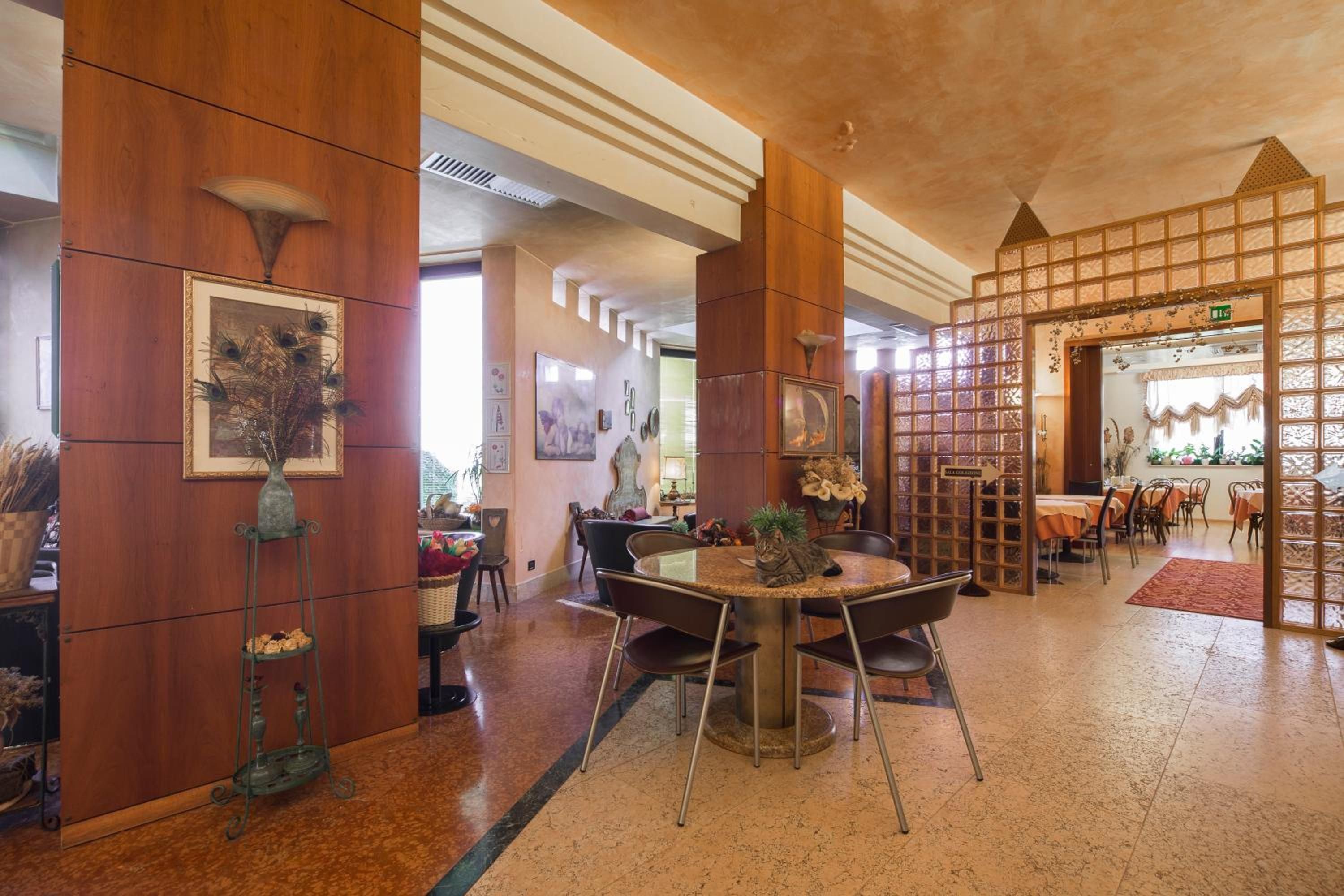 A hotel lobby with a round table, chairs, wooden paneling, and artwork on the walls.