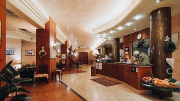 A hotel lobby with a reception desk, seating area, and a decorative wall.