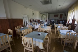 A dining area with multiple tables and chairs, wooden paneling on the walls, and a large mirror. - Hotel La Fonte (Osimo)