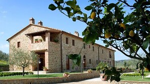 A stone building with a sloped roof, a small porch, and potted plants around the entrance. - I Grandi Di Toscana (Civitella in Val di Chiana)
