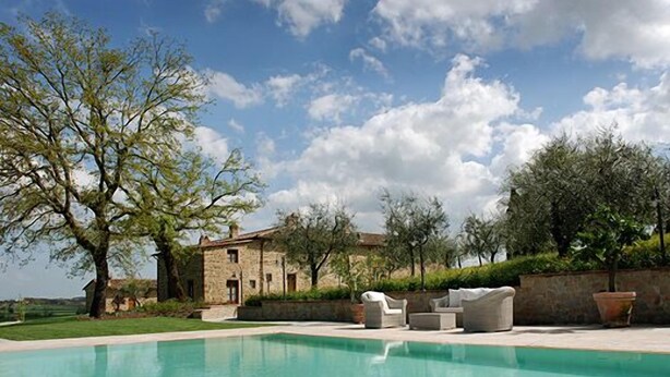 A pool area with outdoor furniture, a stone building, and trees. - I Grandi Di Toscana (Civitella in Val di Chiana)