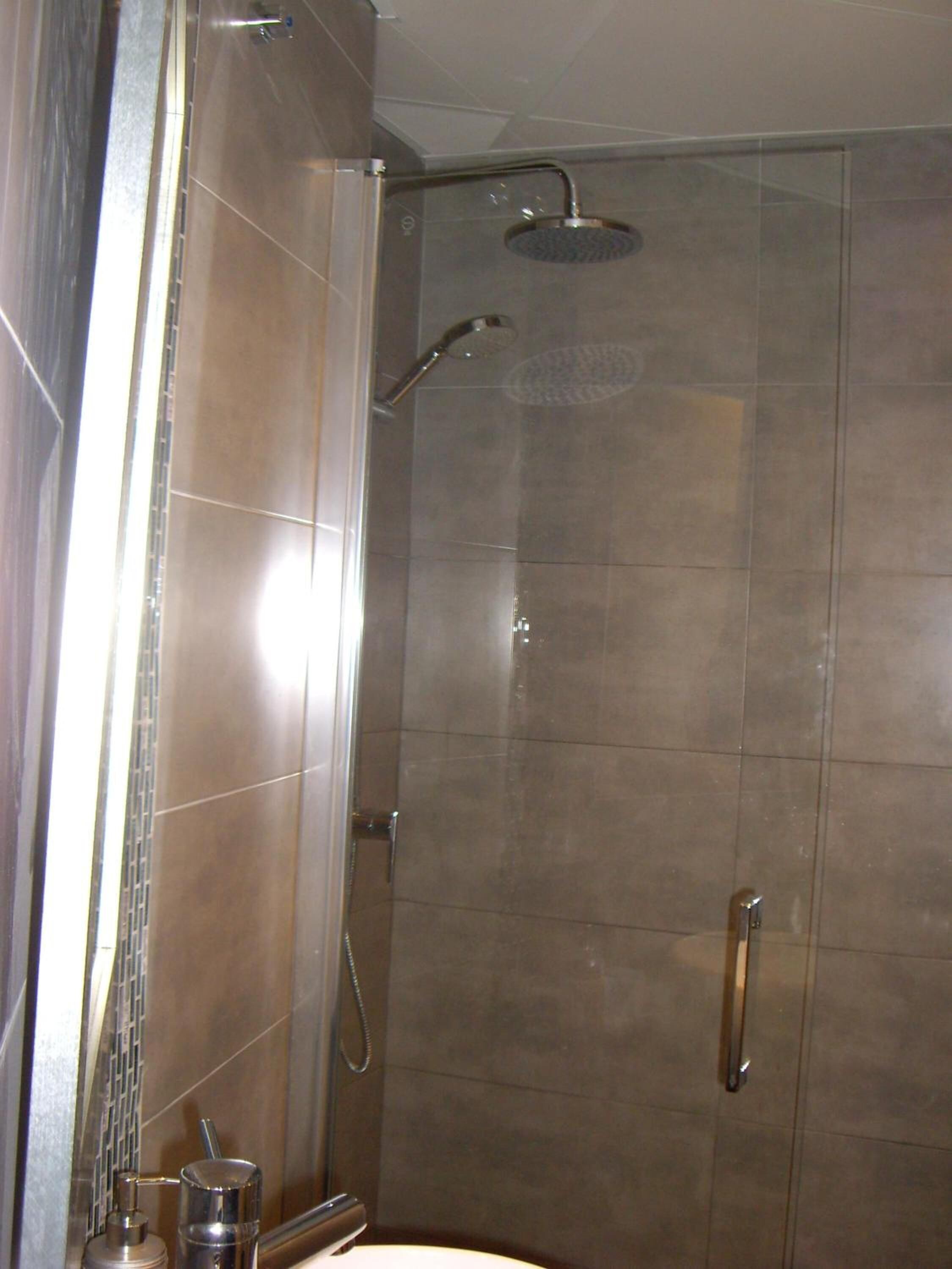 Una ducha moderna con cabezal de ducha de mano y cabezal de lluvia empotrado.