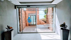Un intérieur moderne avec une entrée dotée d’une porte en verre, un logo représentant une ancre bleue et deux plantes en pot.