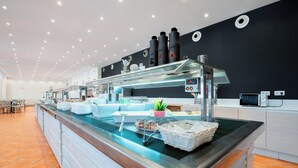 A buffet area with a glass display case, plates, and a microwave. - Dunas de Doñana (Almonte)