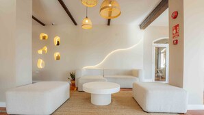 A modern living room with a white sofa, two poufs, a coffee table, and unique wall-mounted lighting. - Dunas de Doñana (Almonte)