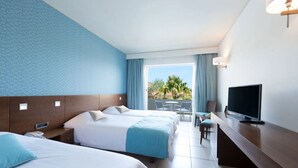 Une chambre d’hôtel avec deux lits, une télévision, un bureau et un balcon avec des meubles d’extérieur.