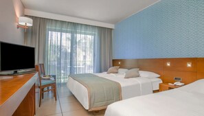 A hotel room with a TV, two beds, a desk, and a chair. - Blue Lagoon Resort (Kos)