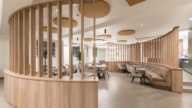 A modern interior with a curved wooden partition, round tables, and a seating area with sofas. - Hotel Mealba Suite & Pool (Saronno)