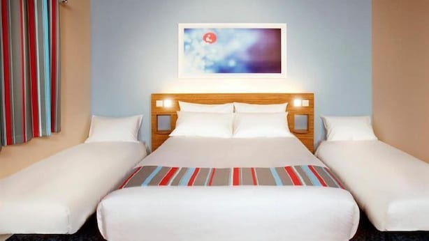 Ein Hotelzimmer mit einem großen Bett, zwei Nachttischen und einem an der Wand hängenden Kunstwerk.