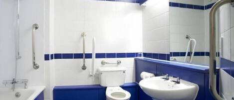 Un baño con inodoro, lavamanos y barras de apoyo.