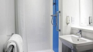 Ein modernes Badezimmer mit Duschkabine aus Glas, einer blauen Tür und einem weißen Waschbecken mit Spiegel.