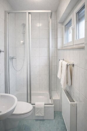 A modern bathroom with a glass-enclosed shower, a white sink, and a toilet. - Hotel Discovery (Stuttgart)