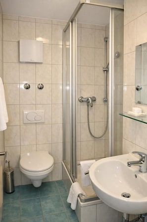 A modern bathroom with a toilet, shower, and sink. - Hotel Discovery (Stuttgart)
