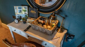 A neatly arranged desk with a clock, remote control, basket of toiletries, and a lamp. - The Bowl Inn (Bristol)