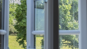 An open window with a view of a garden, outdoor furniture, and a white picket fence. - The Bowl Inn (Bristol)