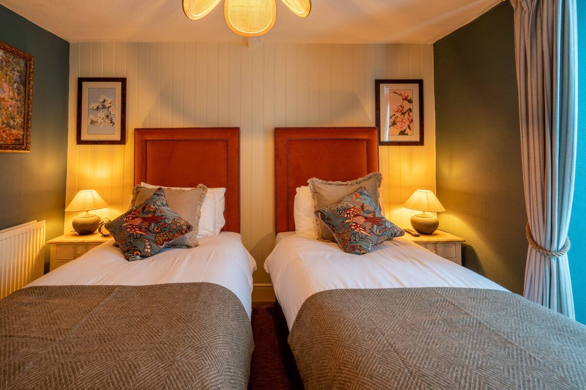 A hotel room with two beds, each with a headboard, bedside lamps, and decorative pillows.
