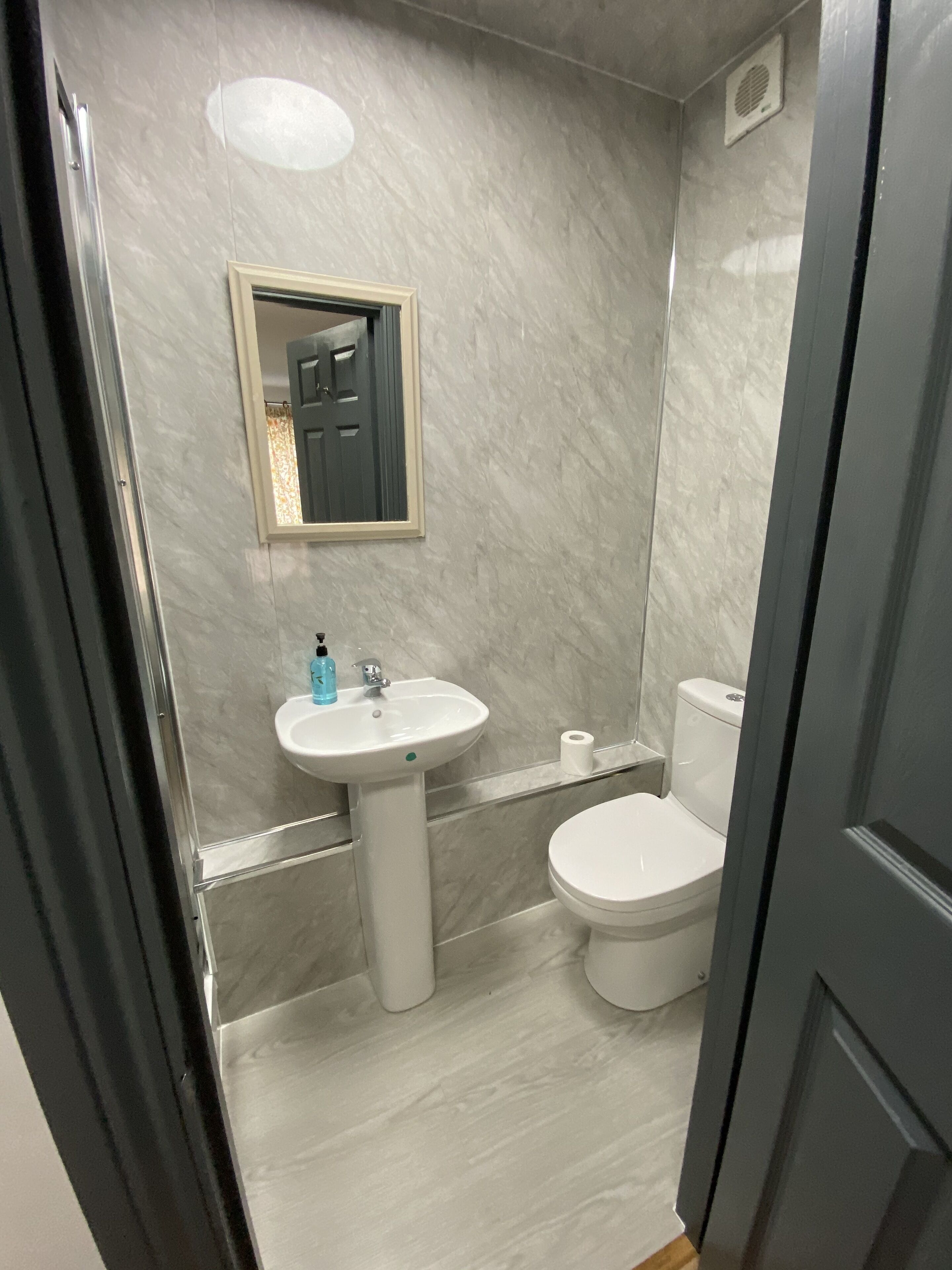 A bathroom with a white sink, toilet, and mirror.