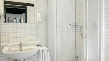 Un baño con lavamanos, espejo y cabina de ducha.