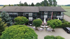 Un edificio de dos pisos con techo de tejas, varias ventanas y zonas de estar al aire libre con sombrillas.