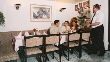 Ein Restaurant mit einer Sitzecke, einem Kellner, der Getränke serviert, und einem Tisch mit einer Blumenarragemement.